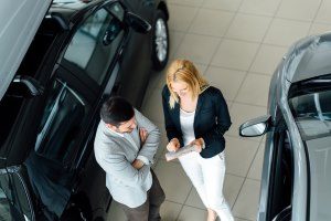 Verkäuferin berät Kunden beim Autokauf